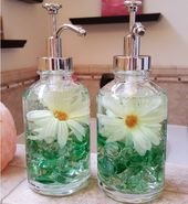 Add a pop of color to your bathroom by filling soap dispensers with glass gems and faux flowers.